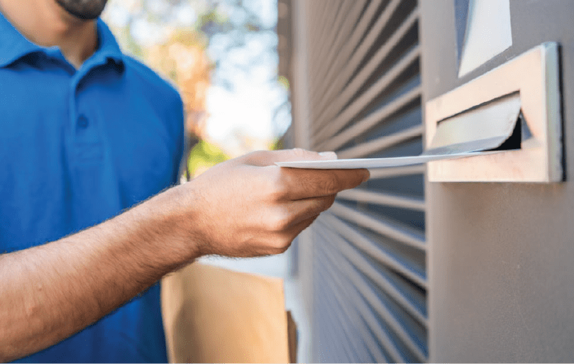 An iPrintPost delivery person leaning against a package of mail that needs distributing